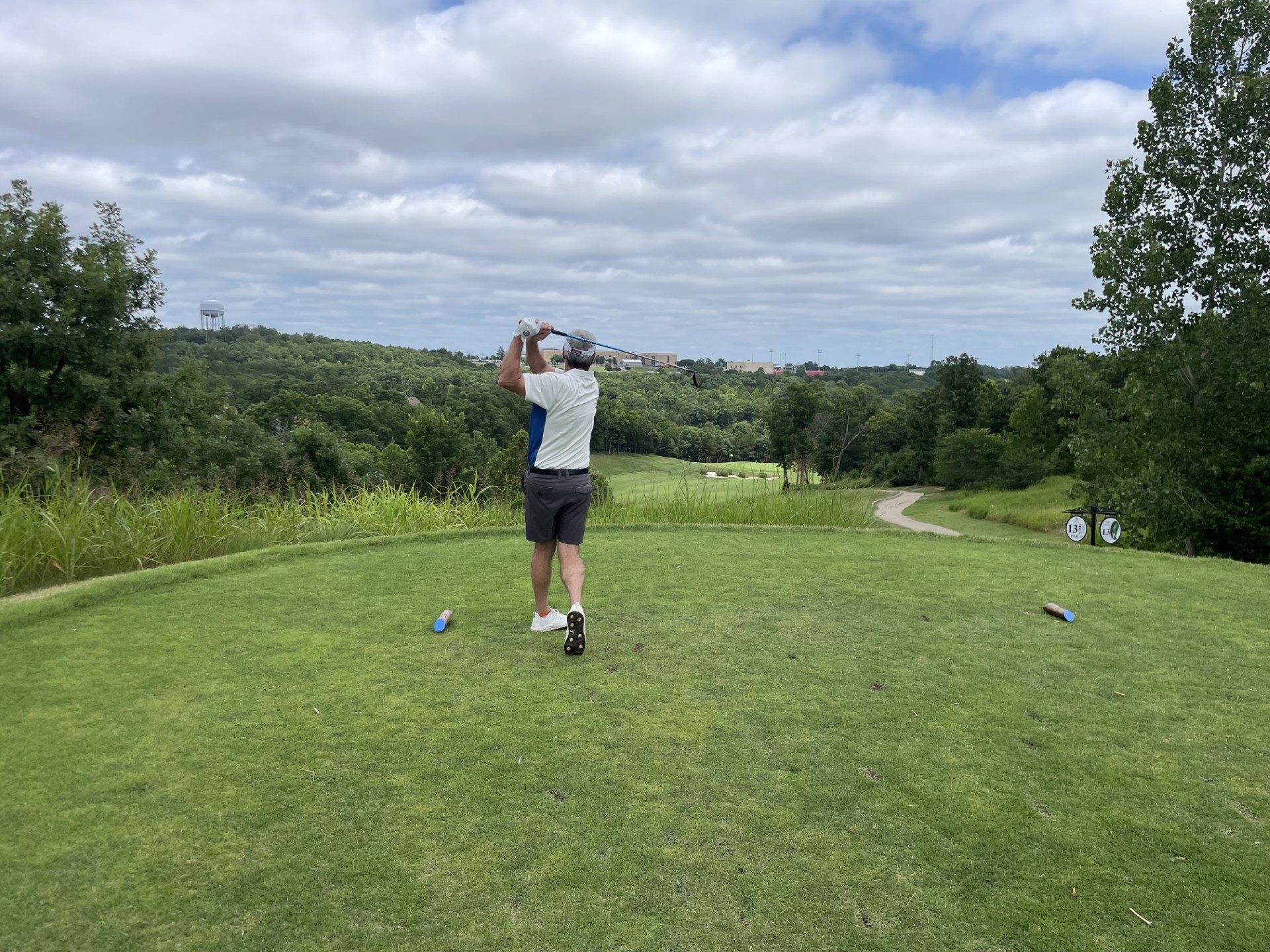 Greg Richard driving over a wooded valley fairway